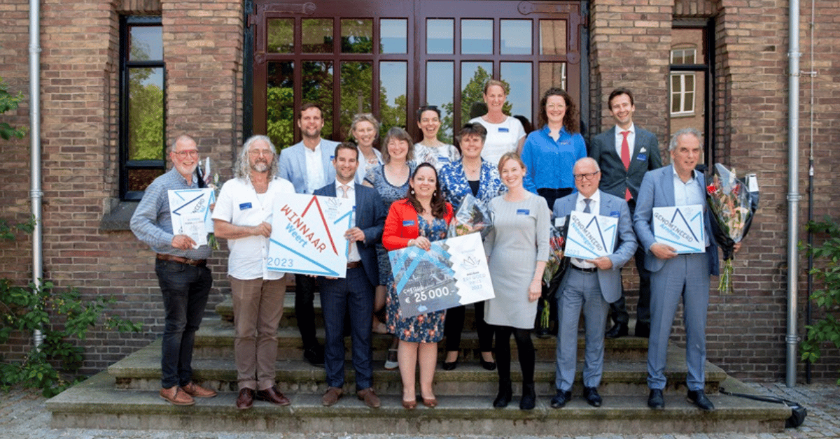 De winnaar van de BNG Erfgoedprijs met een groep mensen staan op de trappen van een gebouw.