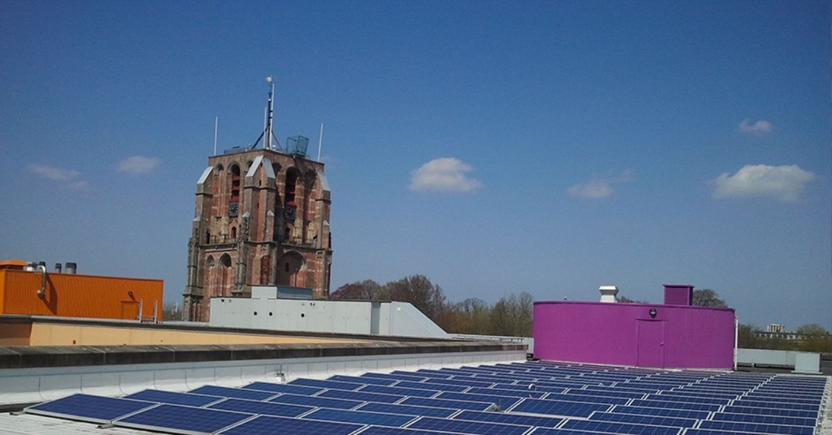 Zonnepanelen op een dak met op de achtergrond de kerktoren van Leeuwarden.
