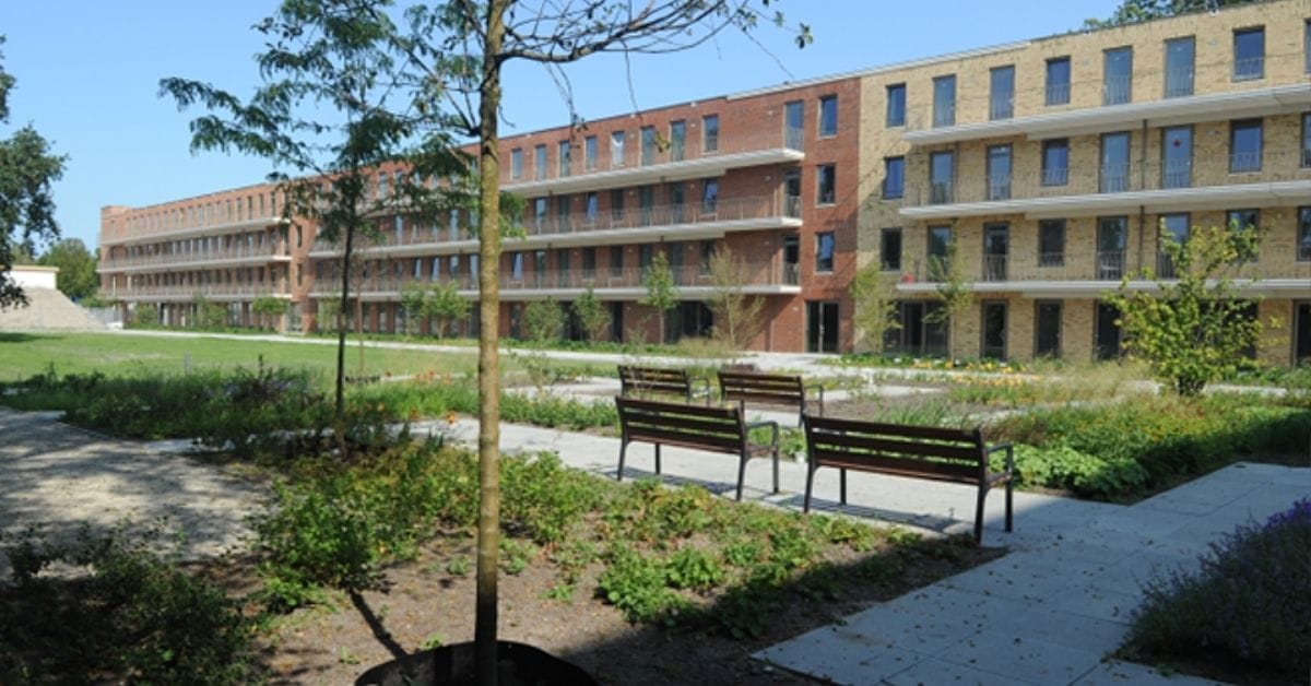 Nieuwbouw appartementen in Leiden. Voor het gebouw staat is een groen grasveld met bankjes.