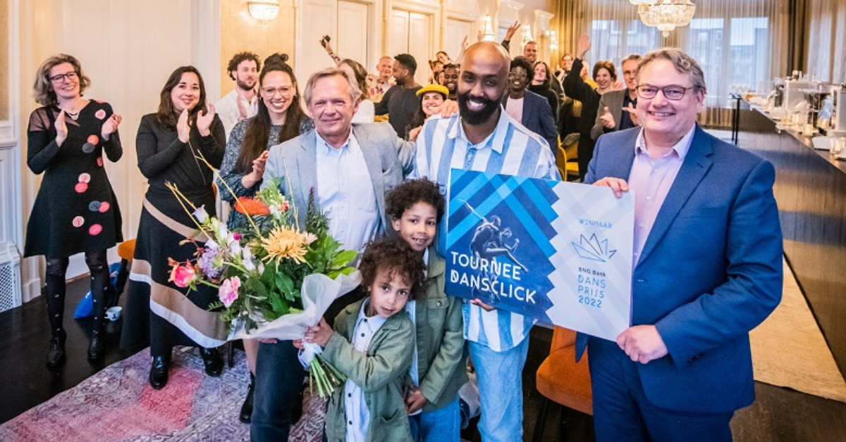 Winnaar van de BNG Dansprijs 2022 Mohamed Yusuf Boss met zijn cheque. Achter hem staan juichende mensen.