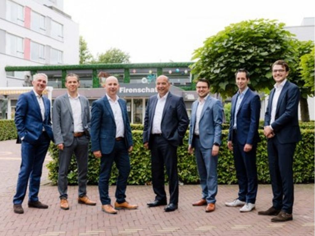 Zeven mannen in pak voor een zorgcomplex.