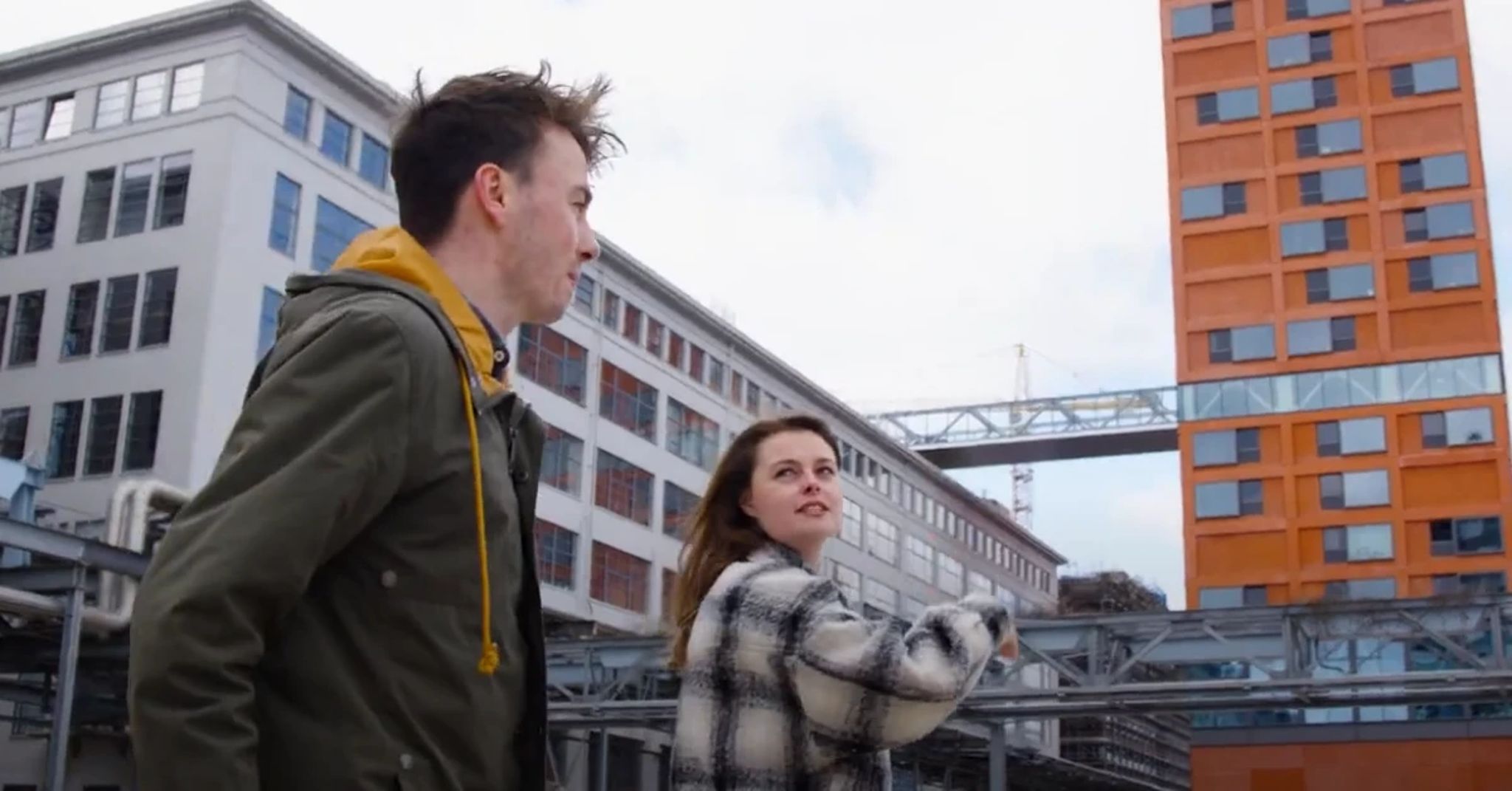 Jonge man en vrouw staan buiten in een industriele omgeving.