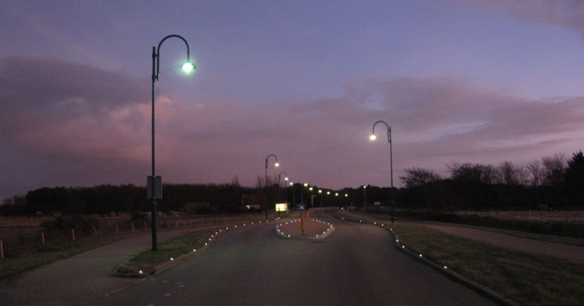 Een straat met straatverlichting in de schemer.