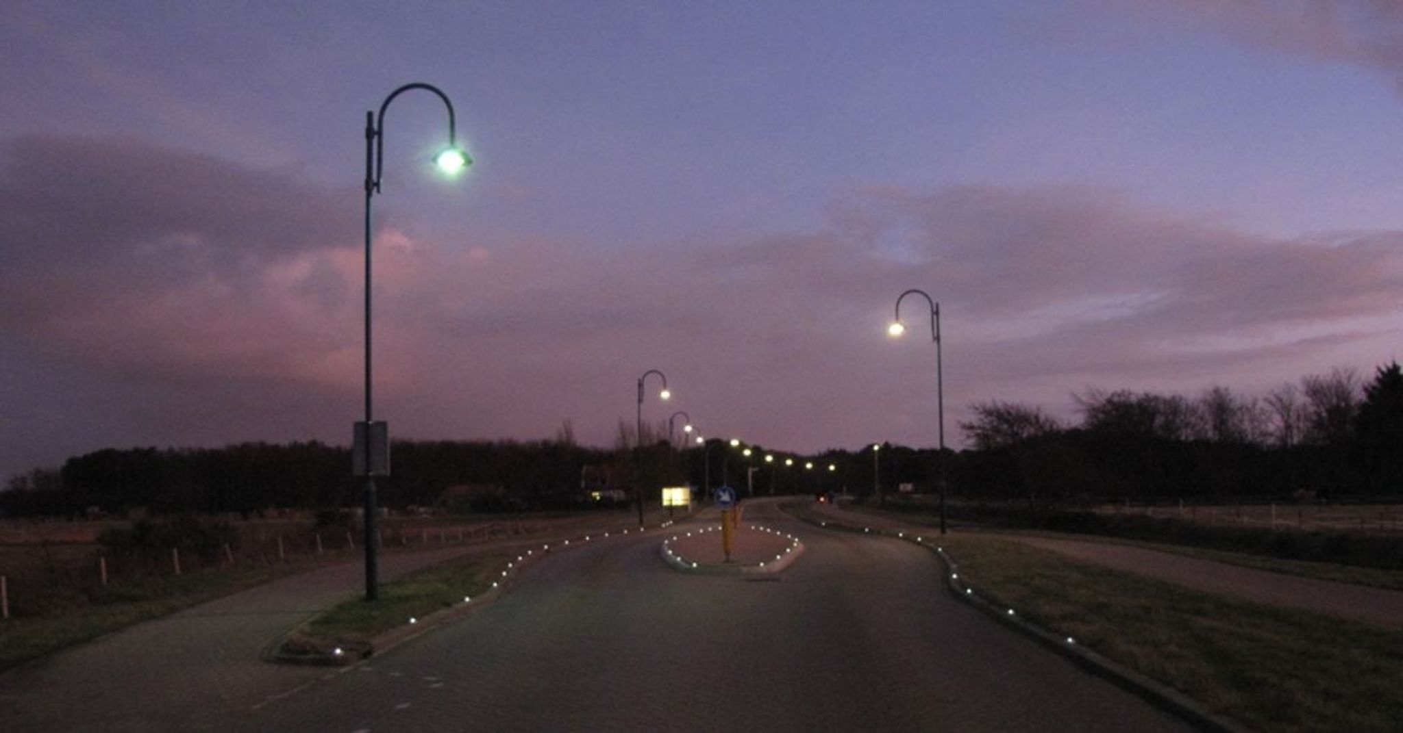 Een straat met straatverlichting in de schemer.