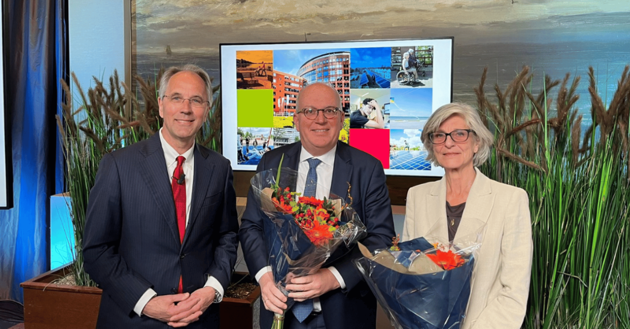 Drie personen met een bos bloemen.
