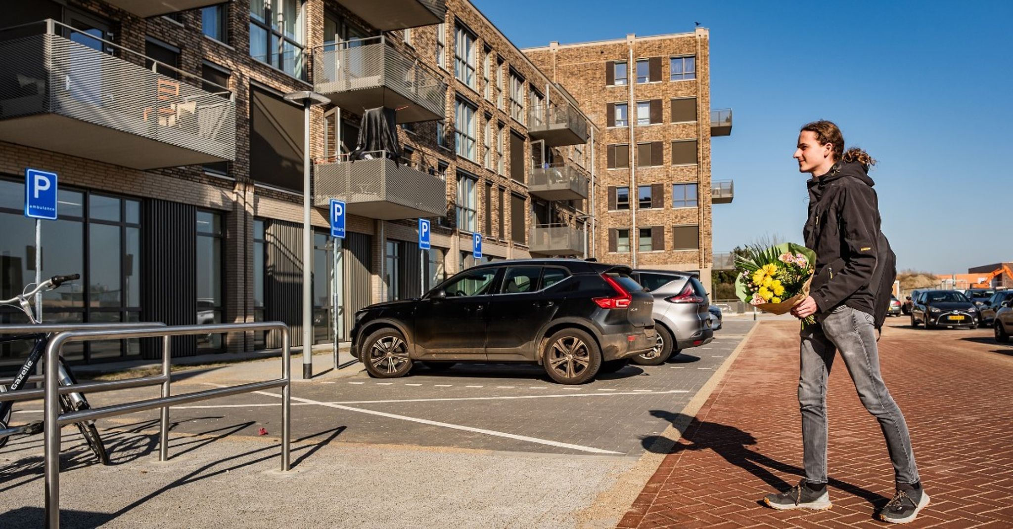 Appartementencomplex met een aantal parkeerplaatsen en auto's ervoor. 