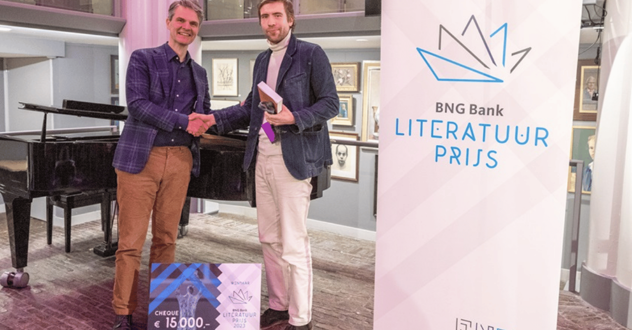 De winnaar van de BNG Literatuurprijs neemt zijn cheque op het podium in ontvangst.